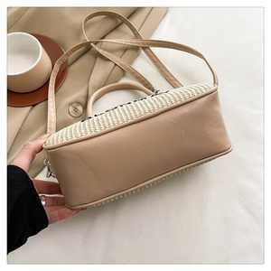 Detail view of woven straw crossbody bag featuring premium leather trim and Bloom text