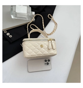 Detail showing mini off-white quilted box bag size compared to an iPhone with gold chain