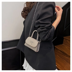 Détail d'un mini sac de soirée en strass avec nœud et bandoulière en chaîne argentée