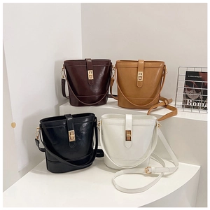 Four colors of vintage bucket bags with metal twist locks displayed on white stands