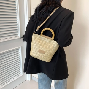 Large straw bucket bag with wooden handles and leather patch on black blazer outfit