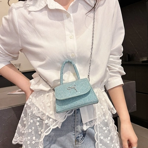 Mini sac à main bleu clair à paillettes avec nœud argenté porté par un mannequin