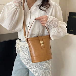 Retro brown bucket tote bag with metal buckle and adjustable strap shown on model
