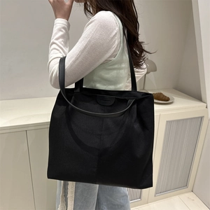 Minimalist black large capacity tote bag shown on model for daily commuting style