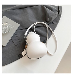 Detailed view of the white gourd-shaped shoulder bag on a minimalist display tabletop