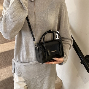 Elegant black glossy leather handbag with gold lettering and adjustable crossbody strap