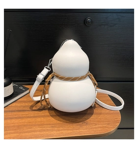 Detail of white gourd-shaped leather crossbody bag with woven rope detail on a wood desk