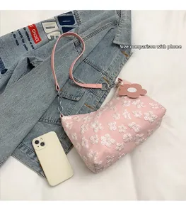 Pink underarm bag size comparison with smartphone and textured floral lace detail