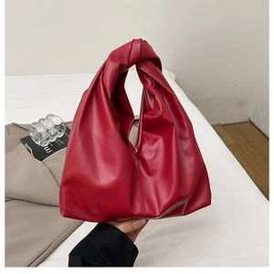 Detail of red ruched cloud bag showing soft leather texture and knotted handle