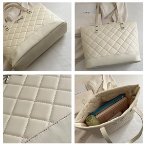 Detail view of off-white quilted tote bag with silver bow accent and large capacity interior