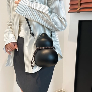 Minimalist black gourd-shaped crossbody bag with woven rope detail on a model