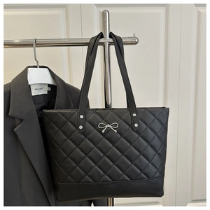 Macro view of black quilted tote bag featuring silver metal bow and stud detailing