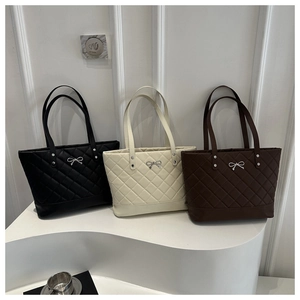 Detailed view of quilted tote bags in black, beige, and coffee with silver bow details