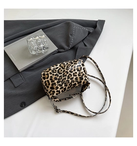 Detail of leopard print crossbody bag with silver hardware on a gray blazer background
