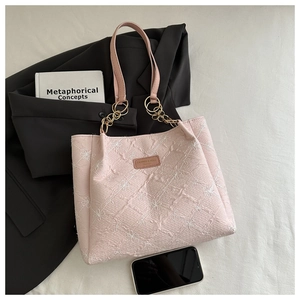 Detailed pink tote bag featuring floral embroidery with leather and gold metal straps