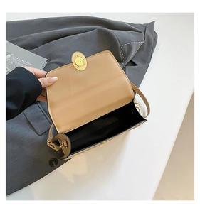 Detail of beige leather bag featuring a gold oval twist lock and sleek black inner lining