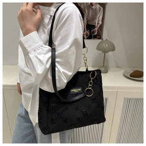 Macro detail of black tote bag featuring shimmering starry texture and gold chain link