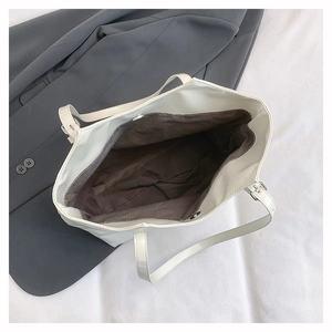 Top view of spacious interior with brown fabric lining of a cream faux leather tote bag