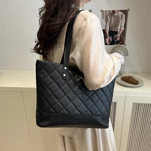 Chic black large capacity quilted tote bag with silver metal bow worn by a model