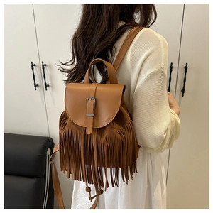 Detail of a brown leather backpack with long tassels and metallic buckle on model back