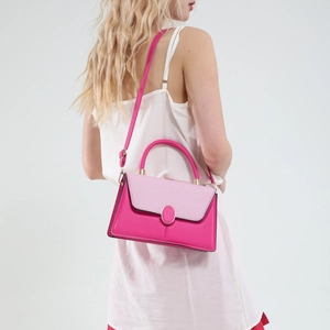 Pink leather handbag with woven texture flap and gold buckle on a model in white dress