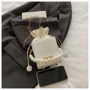 Detail of white snakeskin bucket bag with pearl handle, gold chain and metal feet