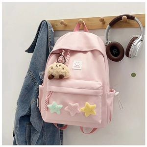 Detail of pink nylon backpack featuring plush stars and a cute brown bear charm