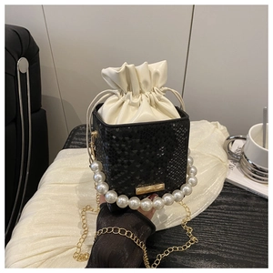 Detail of black snake-pattern bucket bag with pearl handle and golden chain strap