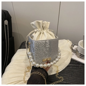 Detail of silver snake-pattern bucket bag with pearl handle and cream drawstring bag