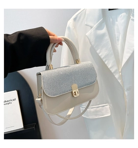 Détail du sac à rabat à paillettes beige avec fermoir doré et poignée supérieure fixe