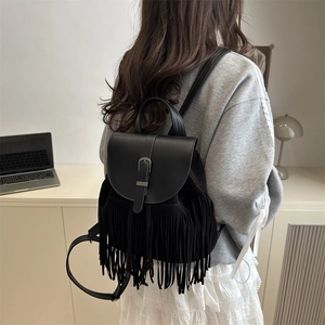 Minimalist black leather backpack featuring long decorative fringe and a metal buckle lid