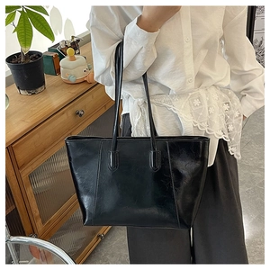Close-up of minimalist black PU leather tote bag with long straps for versatile carrying