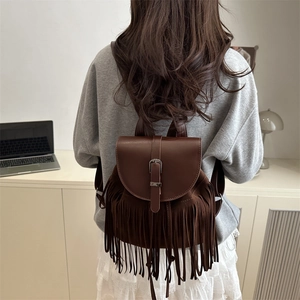 Brown tassel backpack with faux leather flap and suede fringe in a lifestyle setting