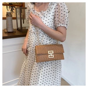 Détail du sac bandoulière en paille tissée avec fermoir doré et bandoulière chaîne