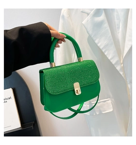 Détail d'un sac vert émeraude avec rabat à paillettes et fermoir rotatif doré chic