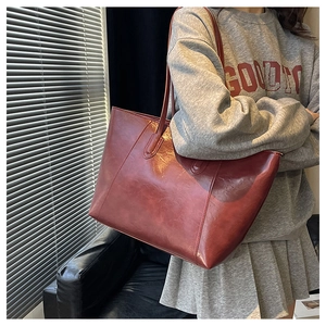 Detail view of glossy burgundy leather tote bag with long handles for shoulder wear