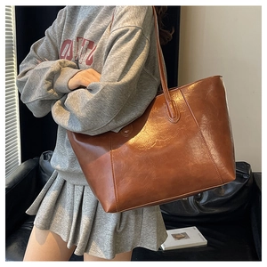 Detail view of large brown PU leather tote bag showing smooth texture and slim straps