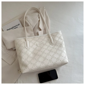 Detail of white tote bag featuring embossed cherry blossom petals and metallic brand logo