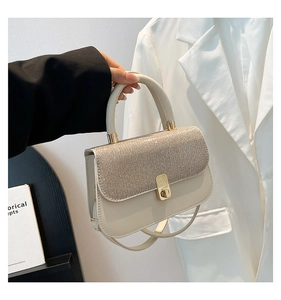 Détail du sac à bandoulière crème avec rabat à paillettes argentées et fermoir pivotant doré