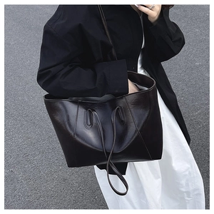 Close-up of a minimalist dark brown tote bag worn over the shoulder for a chic commute