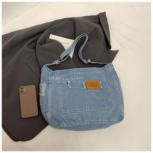 Détail d'un sac à bandoulière en jean bleu avec coutures blanches et bords usés vintage
