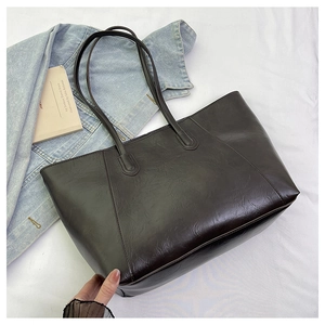 Detail of a large dark brown tote bag with wrinkled faux leather texture for daily commute
