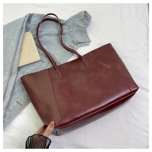 Detail shot of burgundy faux leather tote bag with vertical stitching and slim handles