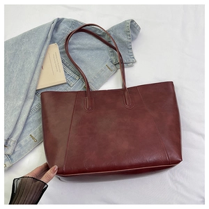 Detail of dark burgundy faux leather tote bag with vintage texture on white fabric