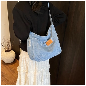 Détail du sac bandoulière en denim bleu clair avec broderie et bords effilochés