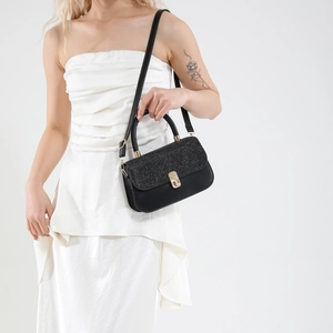 Sac à bandoulière noir élégant avec rabat pailleté et boucle dorée sur fond minimaliste