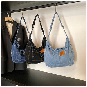 Detailed close-up of three large denim tote bags with leather patches and adjustable straps