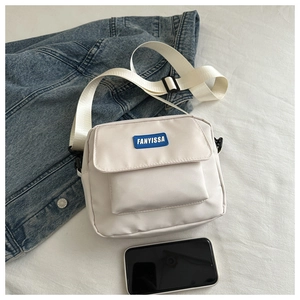Dettaglio della borsa a tracolla in nylon bianco con logo blu e cinturino in tessuto