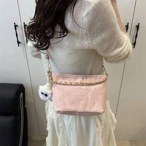 Sac seau rose en nylon à chaîne avec charme en peluche sur une tenue blanche