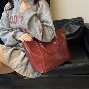 Minimalist vintage burgundy leather tote bag for women showing a stylish shoulder carry look